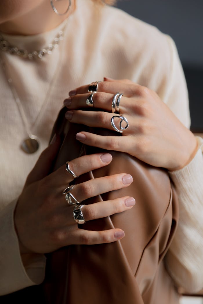 Close-up of elegant hands holding a leather material, adorned with stylish silver rings.